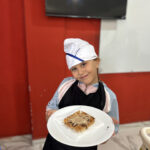 Elite d'Or children French class student smiling proudly with her homemade pancake after a cooking vocabulary lesson Dellys Algeria (2)