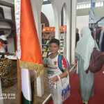 Elite d'Or student posing with the International Book Fair flag Algiers Algeria