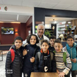 Elite d'Or students in the academy courtyard with their teacher smiling and happy