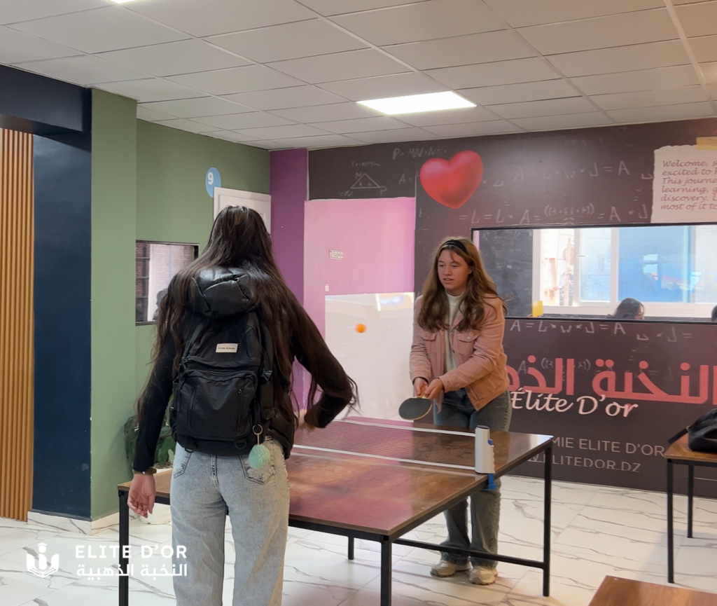 Elite d'Or two students playing ping pong inside the academy recreational area